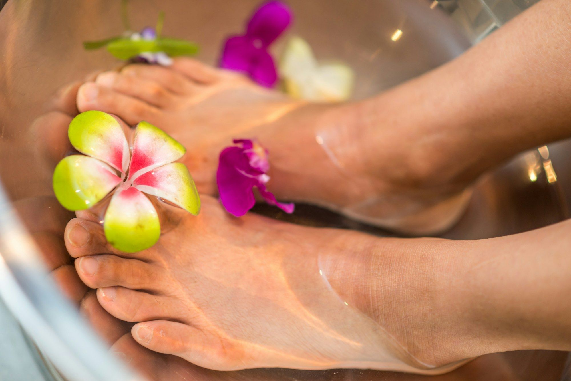 Zwei Füße in einer Schale mit Wasser und Blüten